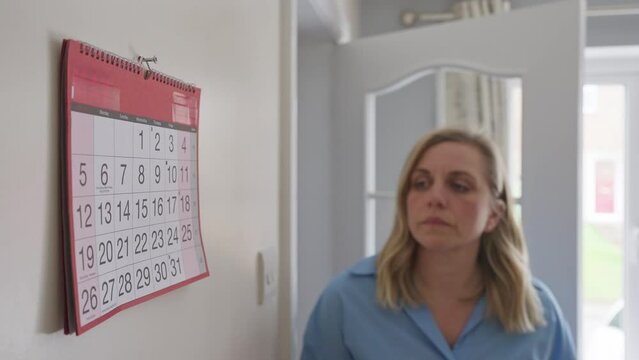 Menopausal Mature Woman With Poor Memory Looking At Calendar At Home