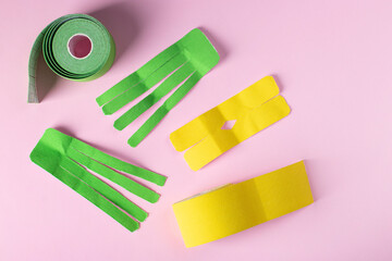 Rolls kinesiology tape in shape of an octopus and letter X for lymphatic drainage taping on pink background. Flat lay, top view, copy space