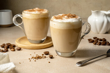 Two glass cups with coffee drink, latte with milk foam and cinnamon 