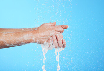 Fototapeta premium Woman, handwashing and water drops with soap isolated on blue background with skincare and hygiene. Cleaning hands, hydration and wellness with mockup, shower and foam product, dermatology and health