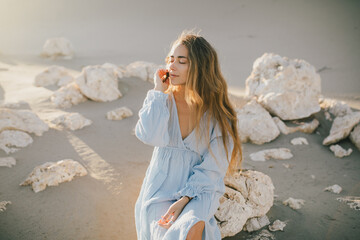 Woman with long hair in a stylish dress poses in the desert sands.