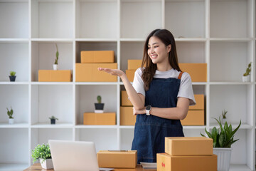 Fototapeta na wymiar Happy young Asian woman entrepreneur, Smile for sales success after checking order from online shopping store in a smartphone at home office, Concept of merchant business online and eCommerce