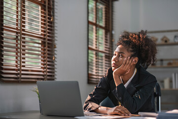 Young African American woman with afro hairstyle looks annoyed and stressed, sitting at the desk,...