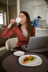 Young female manager working from home, while drinking her coffee.