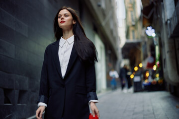 Fashion woman tourist in stylish clothes in a jacket and red beret walking down a narrow city street flying hair and happy travel, French style, cinematic color, retro style.