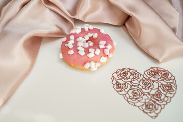 Donut with splashes, on a white background, with a lacy heart and silk fabric