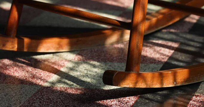 The rocking chair rocks or moves in the room. The sun shines on the rocking chair for elderly people. It is comfortable furniture.