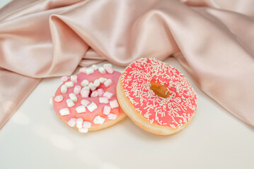 Two donuts with sprinkles and marshmallows, on a white background