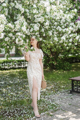An attractive long-haired woman walks in the spring in the park of blooming apple trees.