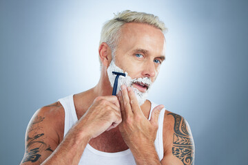 Senior man, razor and shaving beard with cream for grooming, skincare or hair removal against a...