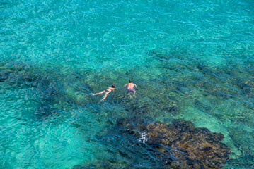 Pareja joven divirtiéndose buceando en las cristalinas aguas turquesas de Fuerteventura en las Islas Canarias mientras disfruta de un cálido día soleado.