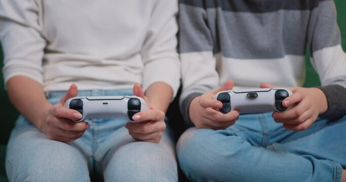 Close up of female and child's gamer's hands holding controles and playing video game. Two joysticks, console, gamers, game