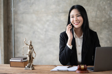 Asian female lawyer talking on the phone consulting with a client in a lawsuit.