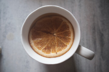 orange slice in herbal tea in white cup on gray background