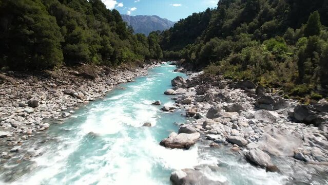 Drone flyover beautiful and wild Copland River surrounded by lush green forest, New Zealand hike.