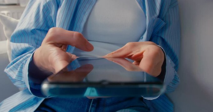 Young woman holding cell phone using smartphone device at home, close-up shot