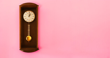 Oldschool clock on a pink wall. Copy space for additional content.