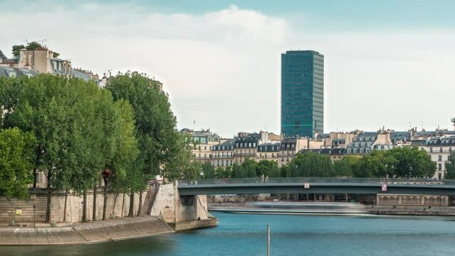 Waterfront of the river Seine near Notre Dame with Saint-Louis bridge timelapse before sunset. High-rise building on a background. View of the houses and trees of the island of Saint-Louis.