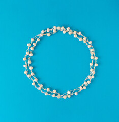 Beautiful round frame of white pearls. White circle on blue background.. Flat lay concept.