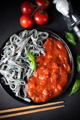 Black pasta with tomato sauce. On a black background. delicious