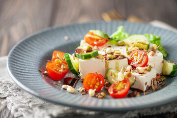 Feta cheese in cubes and vegetables - tomatoes and cucumbers in a plate. Light Greek salad with seedlings