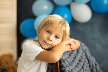 Cute preschool boy, playing with airplane, balloons and birthday decoration