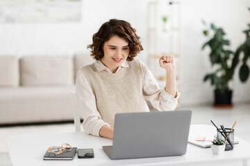 cheerful woman teaching how to speak sign language while having online lesson on laptop.