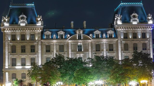 Parvis Notre Dame night timelapse - Place Jean-Paul II. Building opposite to Notre Dame de Paris with night illumination. People walking on the square. Paris. France