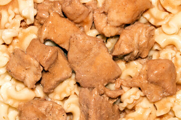 Pasta with meat and gravy.Pasta with meat background.Pasta with pieces of meat in sauce.