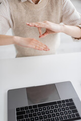 cropped view of teacher showing sign language gesture during online lesson on laptop.