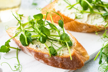 Toast with micro greens, green pea and cream cheese at blue. Healthy food snack, vegetarian. Close up.