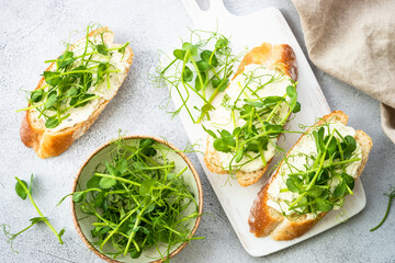 Toast with cream cheese and micro greens at cutting board. Healthy food, vegetarian dish.