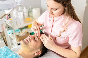 Fototapeta na wymiar Beautician doing face treatment in beauty salon to a male customer.