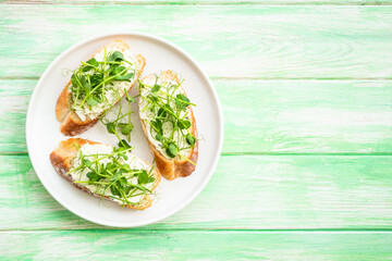 Open sandwich with cream cheese and micro greens at green background. Natural Healthy food, natural vitamins. Top view with copy space.