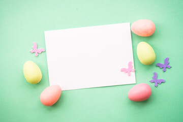 Easter greeting card with eggs, flowers and butterflies at color background. Flat lay image with copy space.