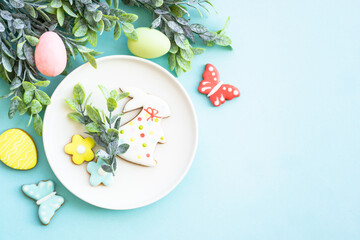 Easter food background. White plate with eggs, spring flowers and easter cookies. Flat lay.