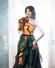 A woman in an orange dress is standing in front of a door