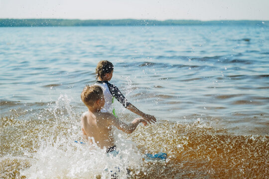 cute caucasian boys running into water with splashes and laughter. Vacatiom on sea side. Happy childhood. Image with selective focus