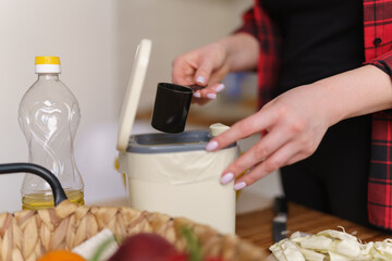 Woman pouring bokashi ferment in a compost bin for recycling. Female person composting organic food...