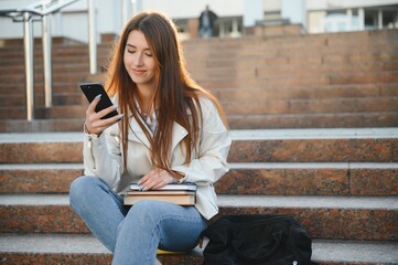 Portrait Of Successful Student. Happy Teenager Girl Posing Holding Books Smiling Looking At Camera Standing Near Modern University Building Outside. Studentship, Modern Education