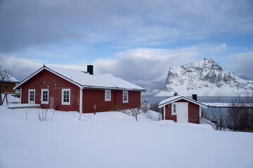 The houses are painted in red and yellow colors with white edges, creating a picturesque scene. Lofoten island during winter. Image for travel and tourism promotions.