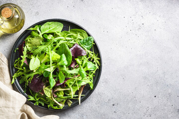 Fototapeta na wymiar Green salad, fresh leaves in black plate. Top view with copy space. Healthy eating.