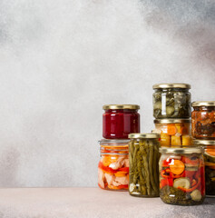 Preserving vegetables for the winter, canned vegetables in jars on a light background, pickled or fermented vegetables, copy space