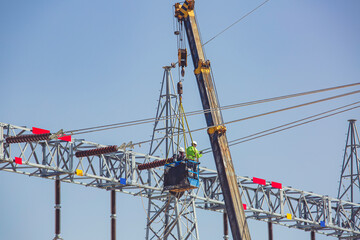 Male workers Installation of high-voltage transmission electricity poles on the crane