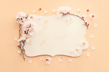 top view of cherry blossom tree flowers and empty board over yellow pastel background. For mock up, copy space