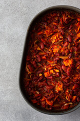 Healthy breakfasts and lunches, stewed red beans with carrots, onions and tomatoes, top view of an oval ceramic roaster with stewed legumes