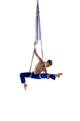Artistic performance. Young man, acrobat training with aerial ribbons, doing gymnastics tricks against white studio background. Concept of art, sportive lifestyle, hobby, action and motion, beauty