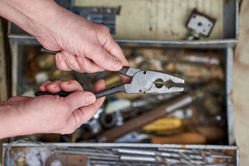 The master holds pliers in his hands