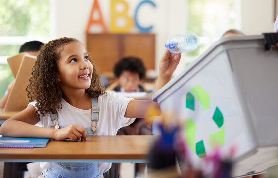 Learning, recycle bin and girl in classroom throwing trash for cleaning, climate change or eco friendly in school. Recycling plastic, smile and education with happy student or kid in kindergarten.