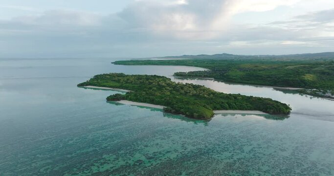 Aerial Scenic View Of Green Island Under Clouds, Drone Flying Upwards Over Tranquil Sea - Nadi, Fiji